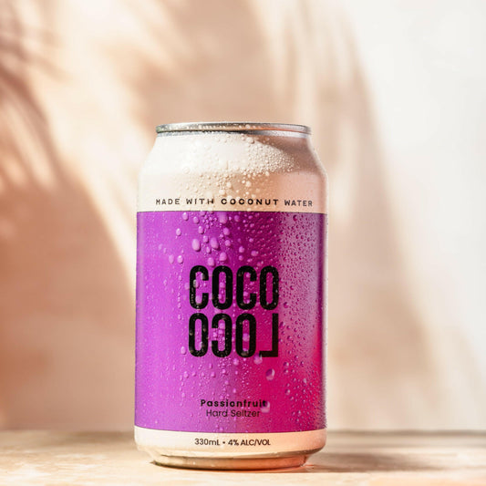 Alcoholic Coconut water can with purple label and black text on a wooden surface
