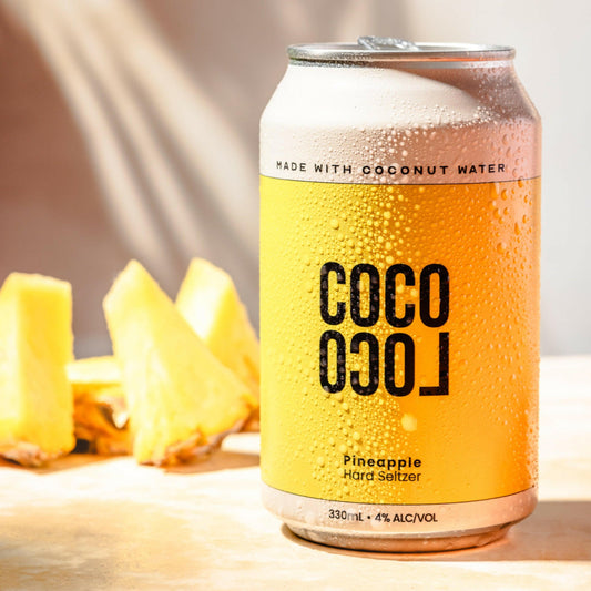 Coco Loco Pineapple Hard Seltzer can with real pineapple pieces in the background