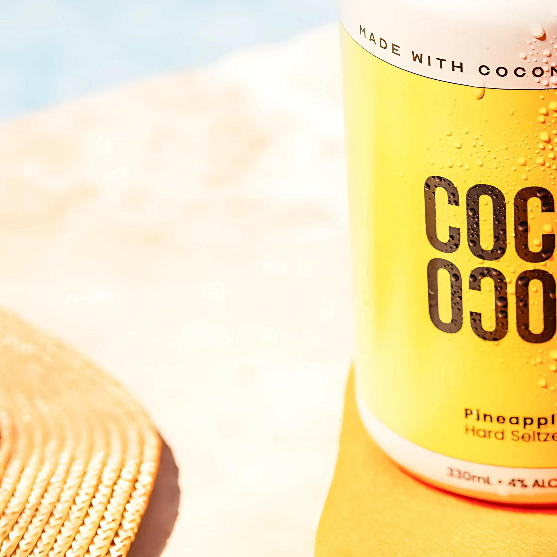 alcoholic coconut water Can drink Coco Loco branding on a sandy background with brim of hat