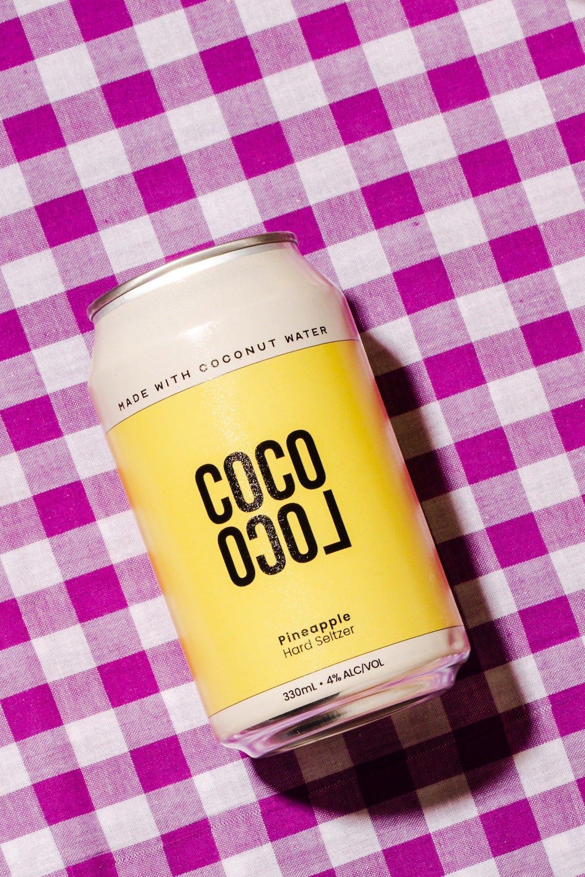 Coco Loco pineapple hard seltzer can on a purple and white checkered background