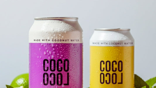 coco loco cans pina colada and passiona spritz with fresh limes and grey background