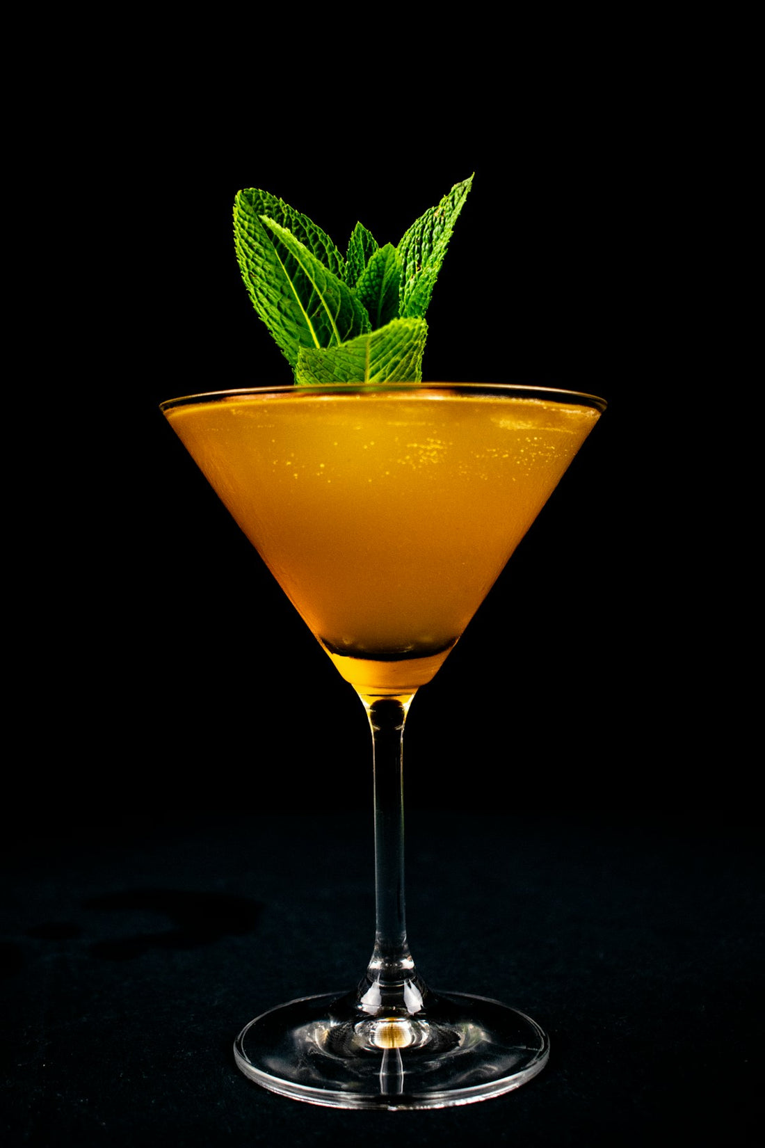 Passionfruit Martini in a golden cocktail glass with fresh mint garnish. Photo by Clovis Wood on Unsplash