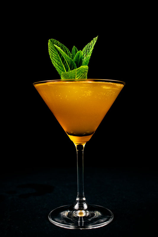 Passionfruit Martini in a golden cocktail glass with fresh mint garnish. Photo by Clovis Wood on Unsplash