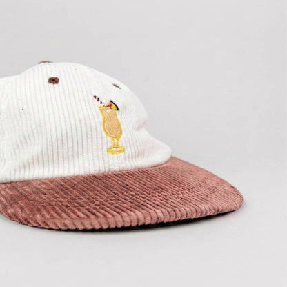 Piña Colada corduroy cap at an angle, showing the dusty pink flat brim and embroidered cocktail glass