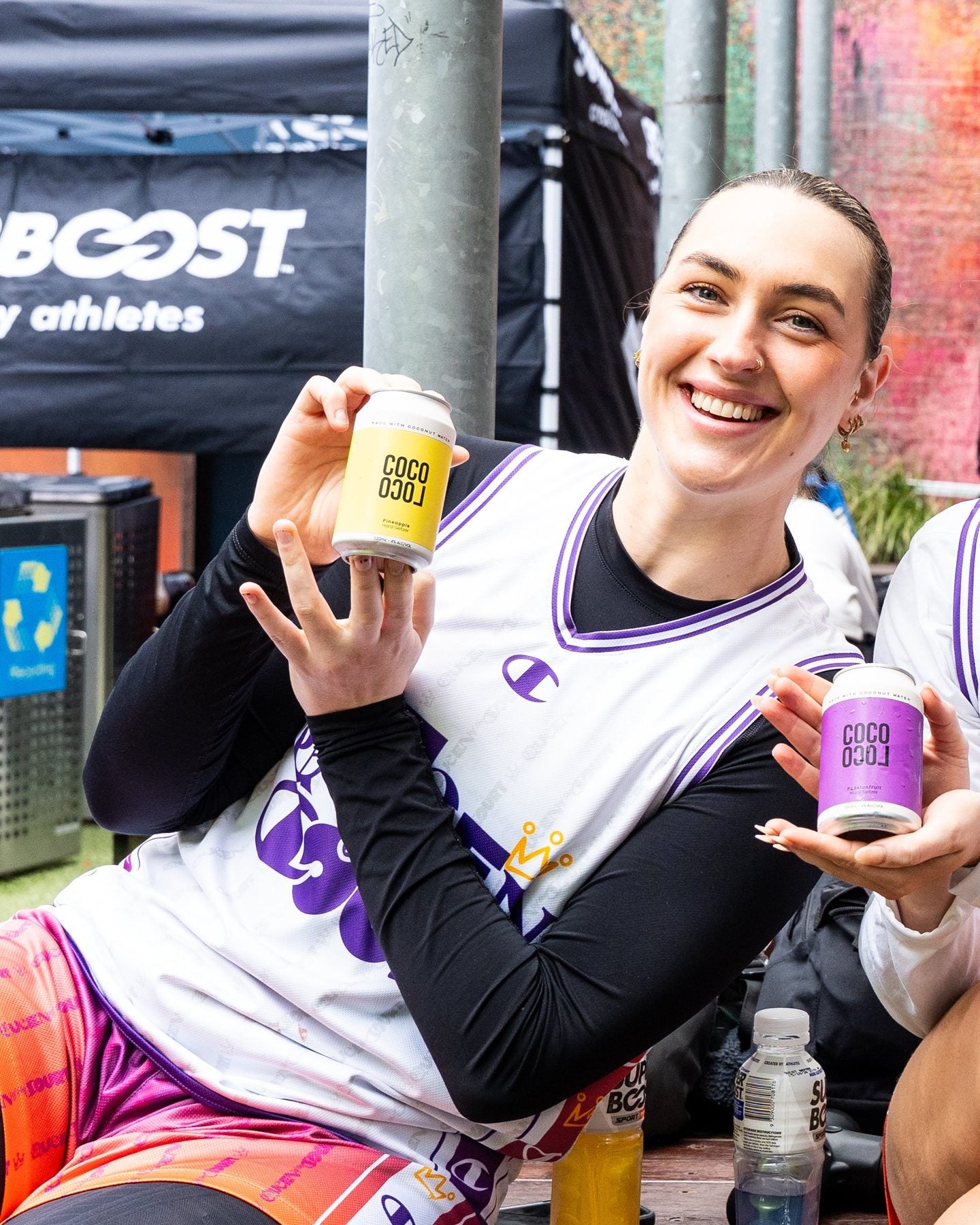 Athlete holding Coco Loco Pineapple and Passionfruit cans courtside