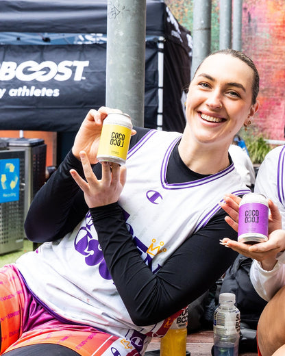 Athlete holding Coco Loco Pineapple and Passionfruit cans courtside