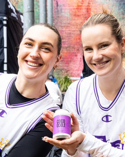 Two women holding a purple can of 'Coco Loco' passiona drink against a colourful background.