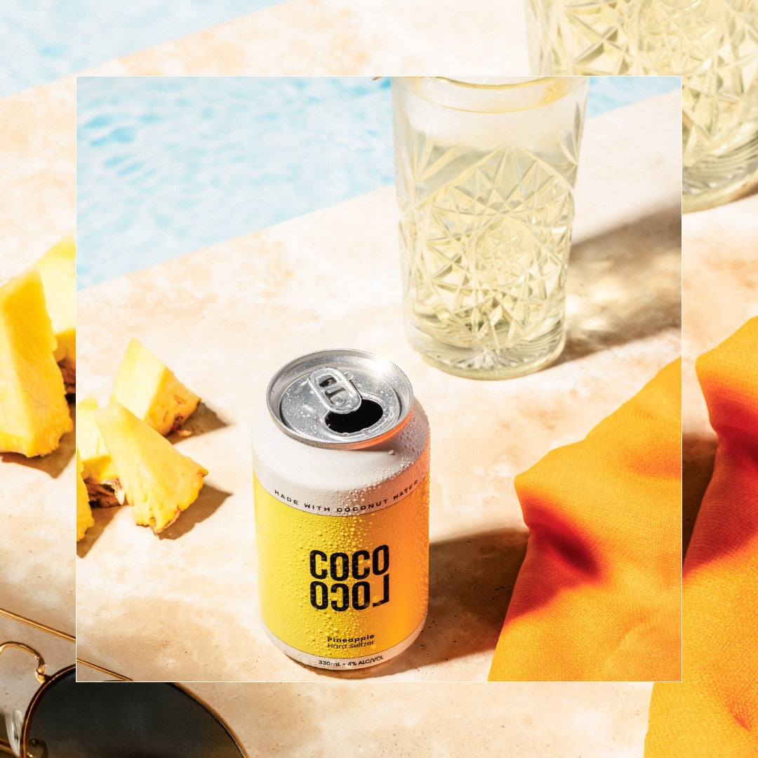 Can of Coco Loco Pineapple poolside with fresh pineapple fruit pieces and glass full of hard coconut water