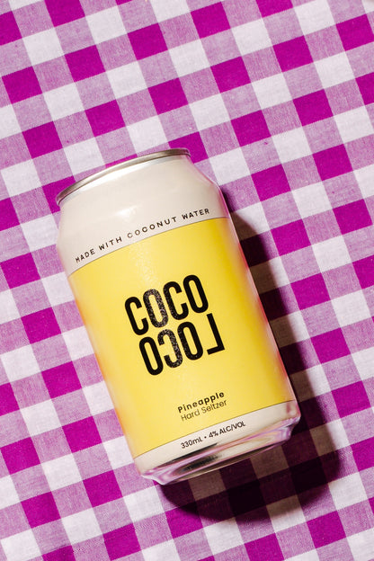 Coco Loco pineapple hard seltzer can on a purple and white checkered background