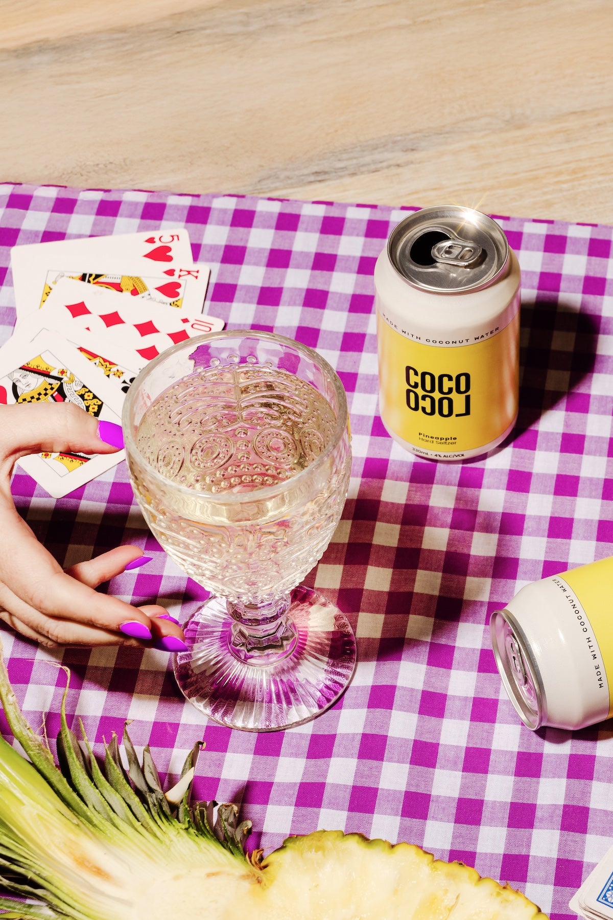 coco loco pina colada can with a glass of a clear drink on a checkered tablecloth.