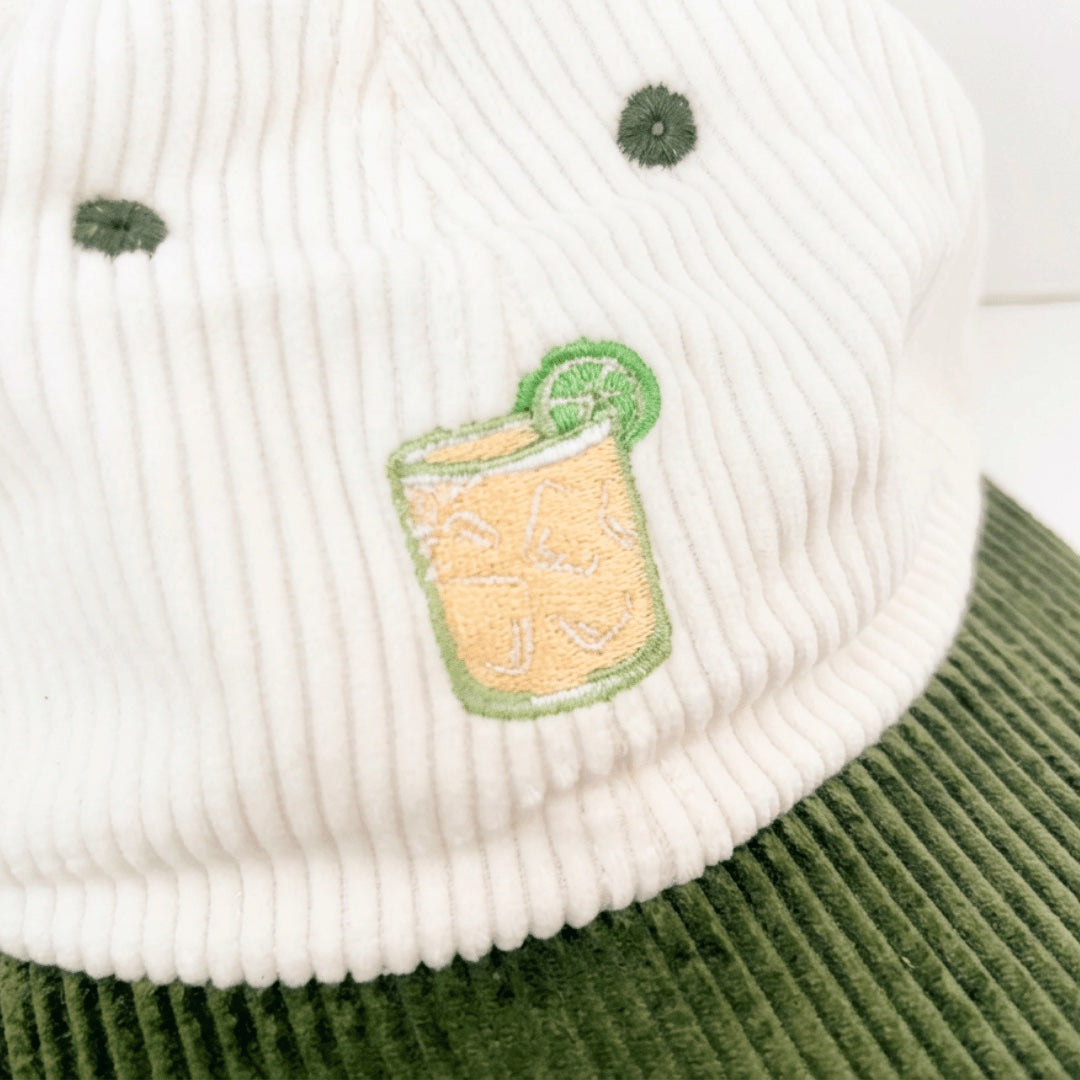 Close-up of the embroidered margarita, a tumbler of ice with a lime wheel, stitched on white corduroy