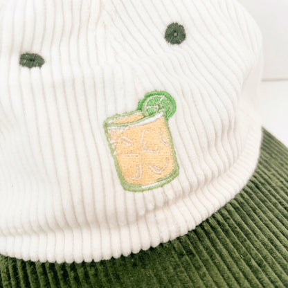 Close-up of the embroidered margarita, a tumbler of ice with a lime wheel, stitched on white corduroy